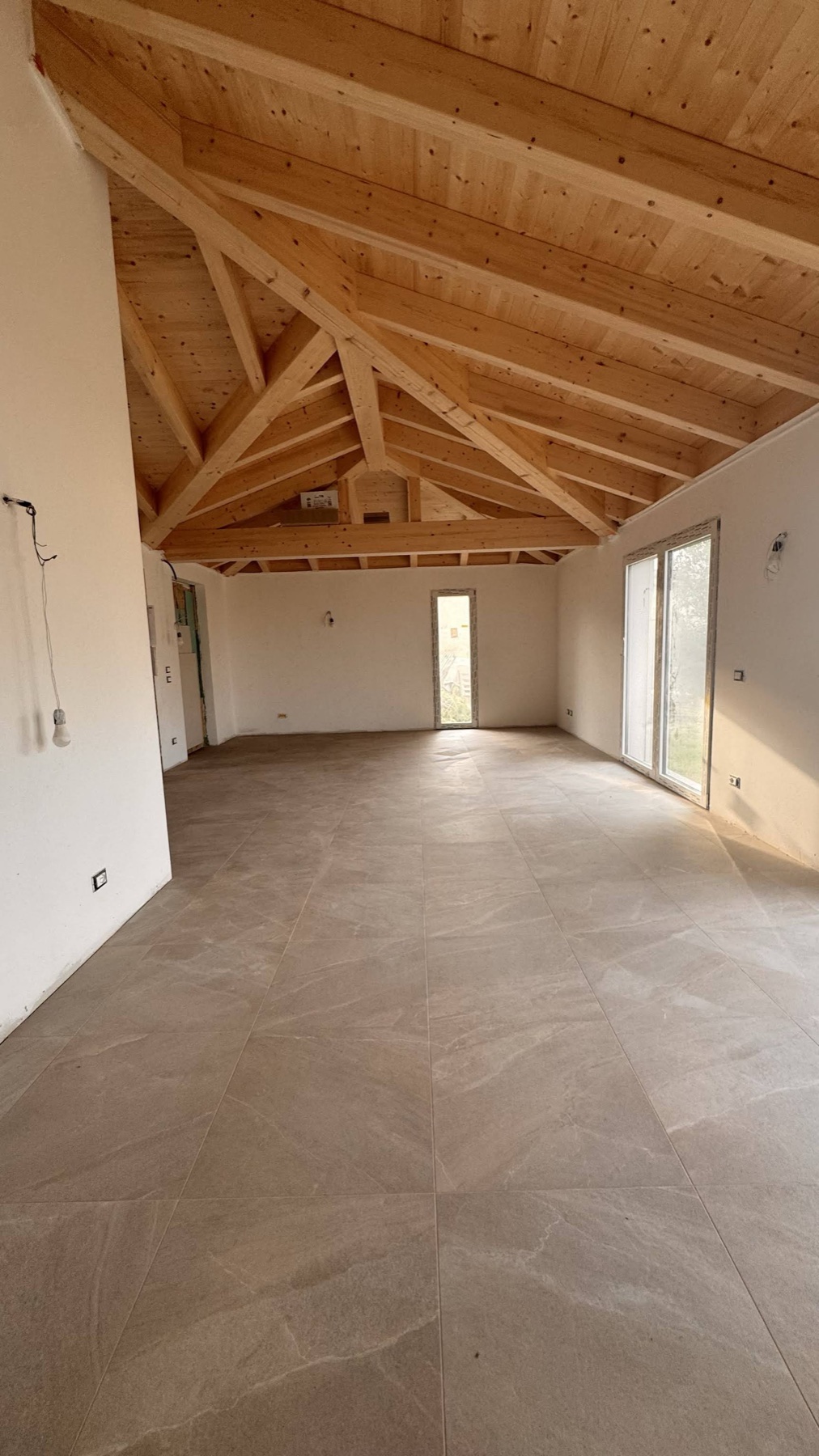 Ambiente luminoso con tetto in legno a vista e grande pavimento